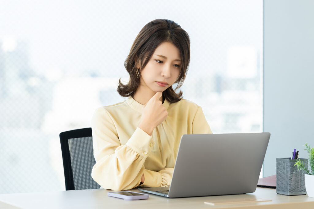 パソコンを使いながら考える女性