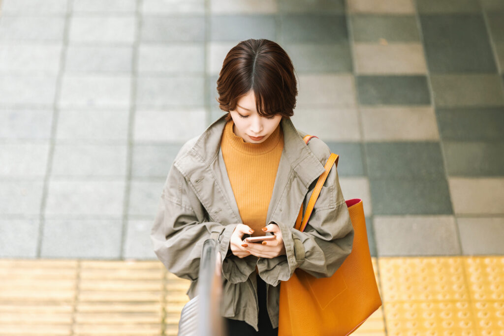 秋の街でスマホを使う女性