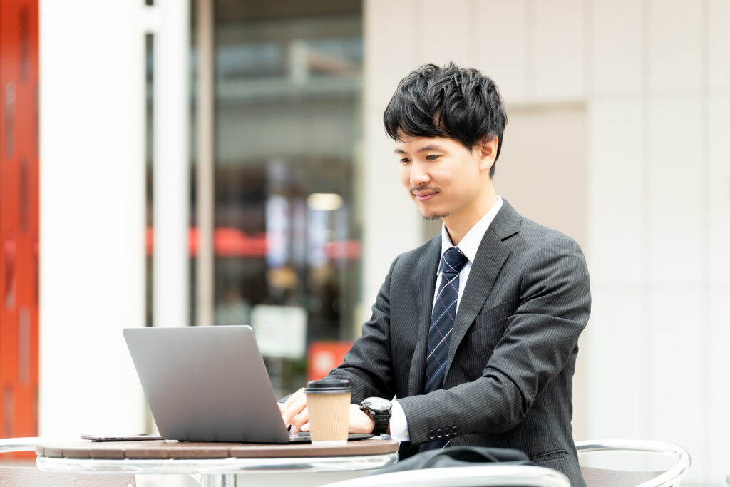 テラス席でパソコンを使う男性ビジネスマン
