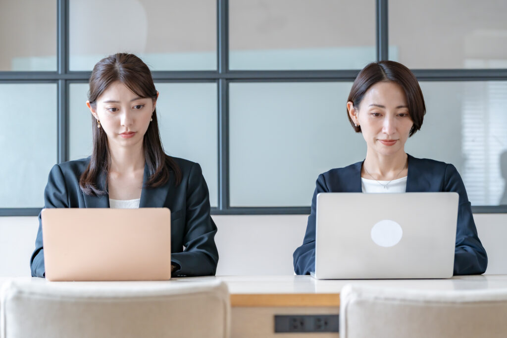 並んでパソコンを打つ女性