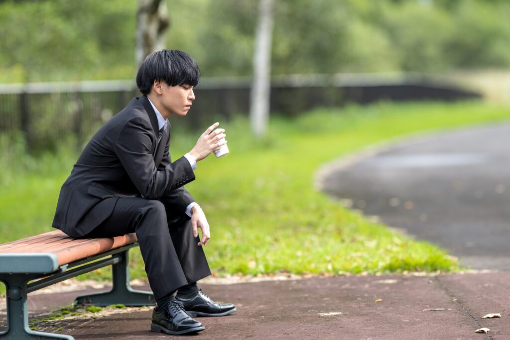 ベンチで珈琲を飲むビジネスマン