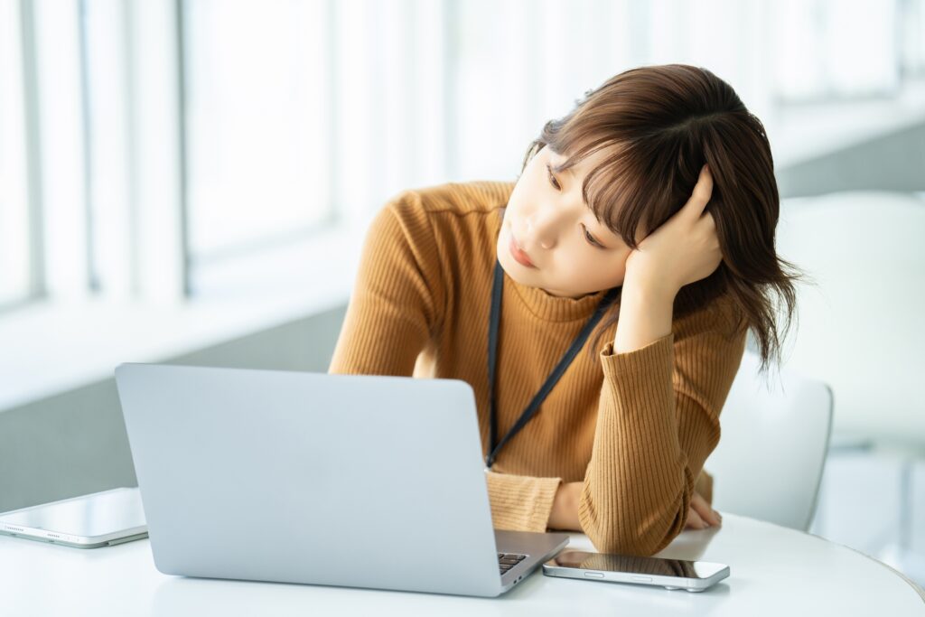 パソコンを使いながら考える女性