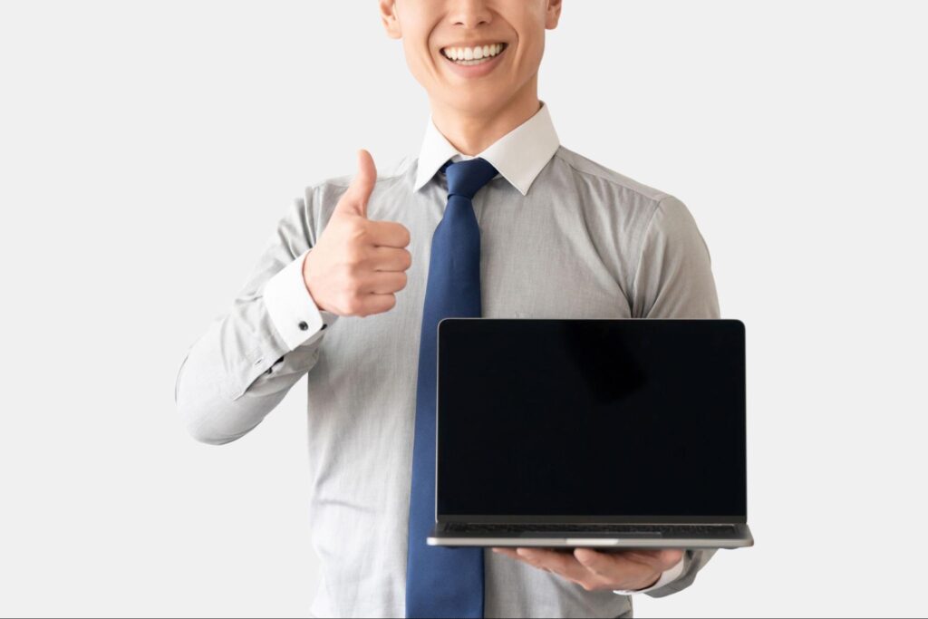 パソコンを持っていいねのポーズをする男性