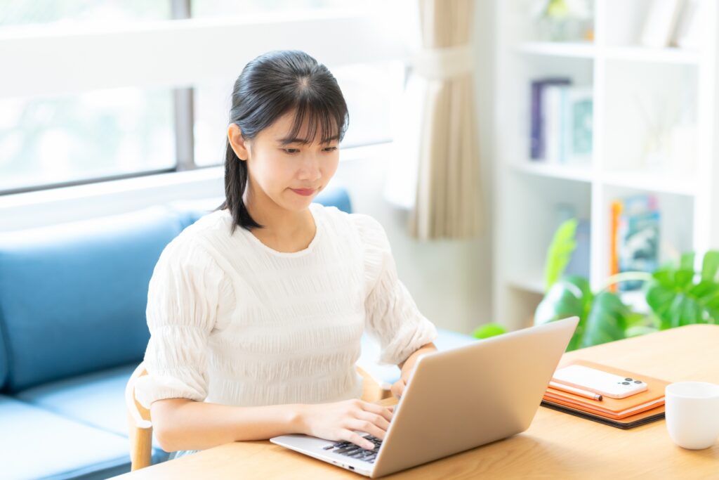 リビングでパソコンを見る大学生の女性