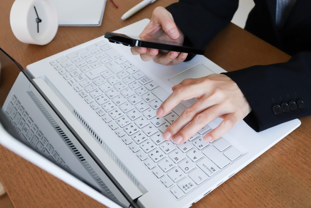 パソコンを操作しながらスマホを操作する男性