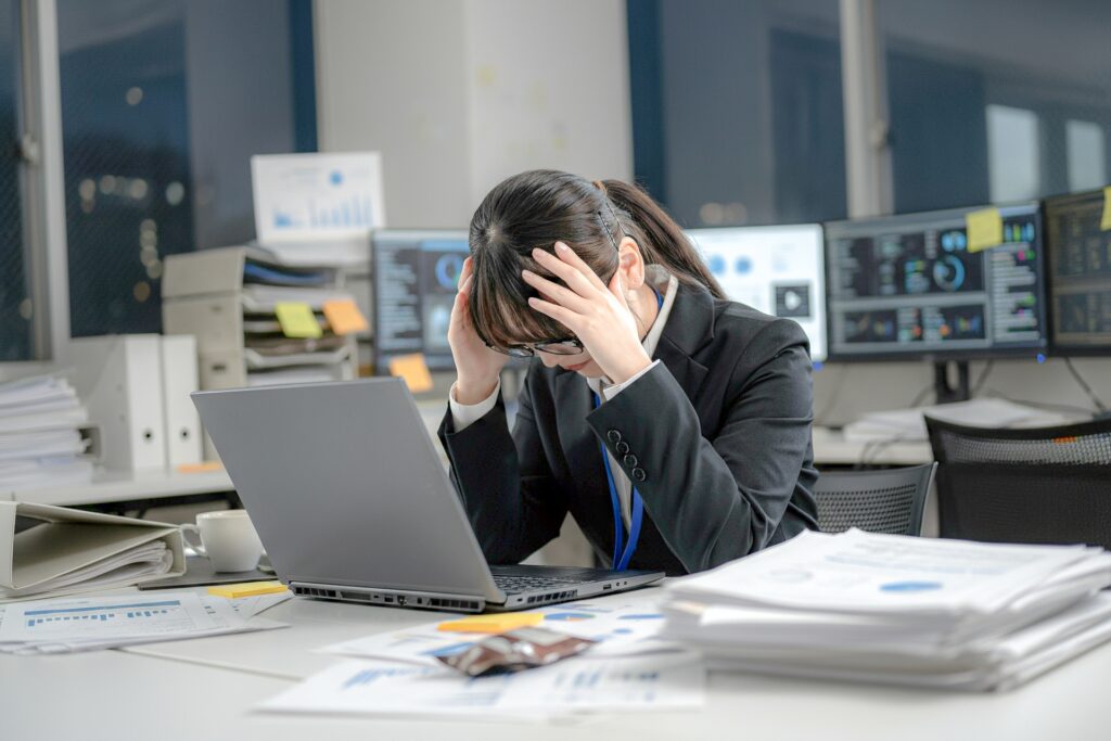 雑多な机で悩むビジネスウーマン