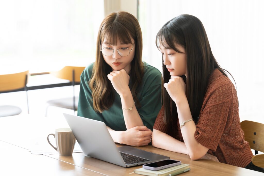 パソコンを使いながら考える2人の女性