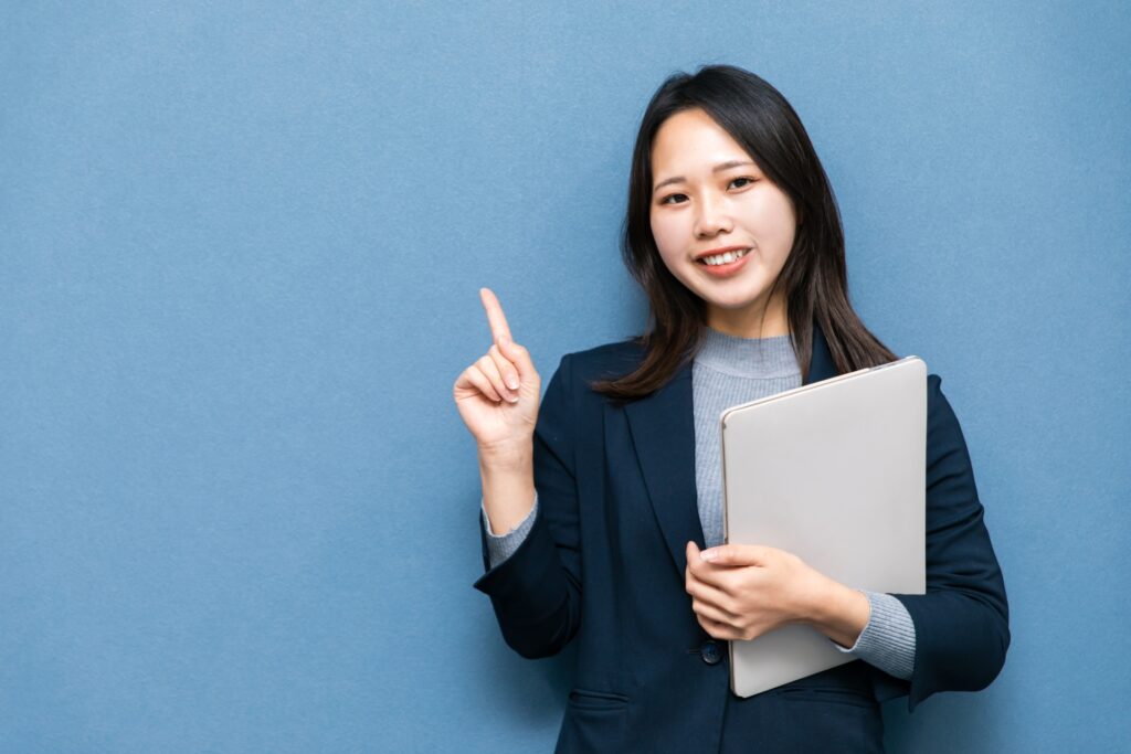 パソコンを持ってジェスチャーする女性