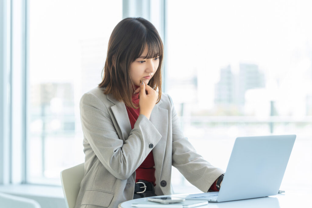 パソコンを使いながら考える女性