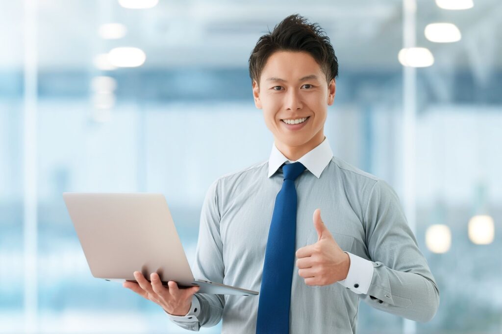 パソコンを持っていいねのポーズをする男性