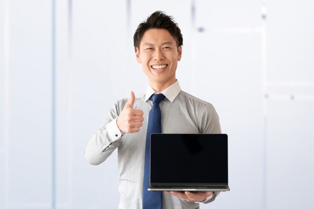 パソコンを持っていいねのポーズをする男性