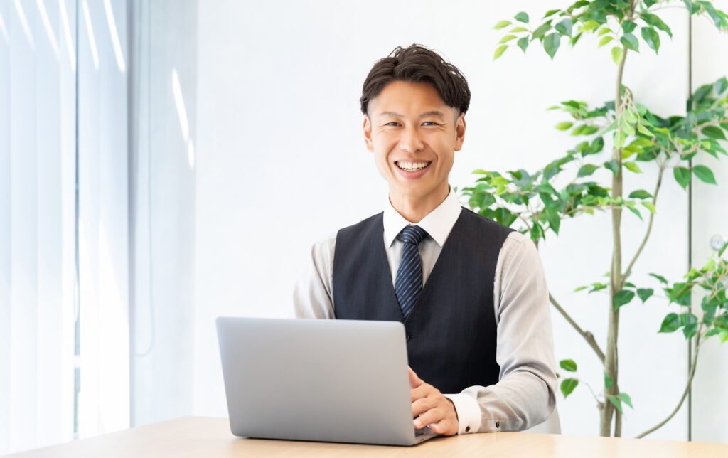 パソコンを使う笑顔の男性ビジネスマン