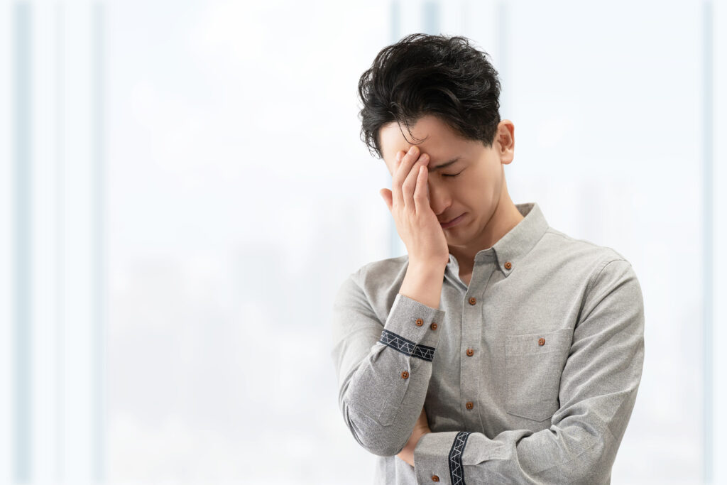 頭を押さえて悩む男性ビジネスマン
