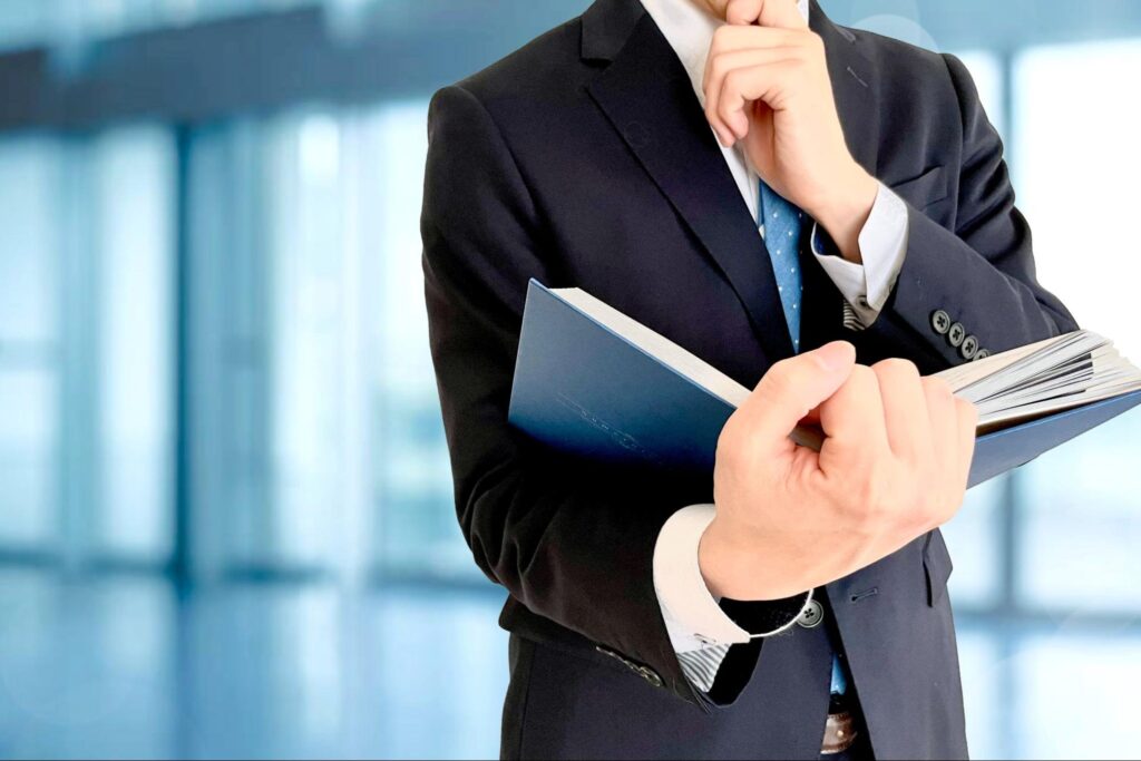 本を開くビジネスマンと会社の背景