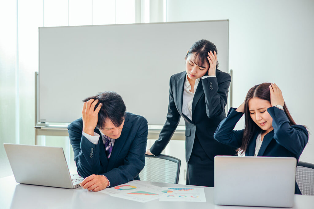 頭を抱えるスーツ姿の男女