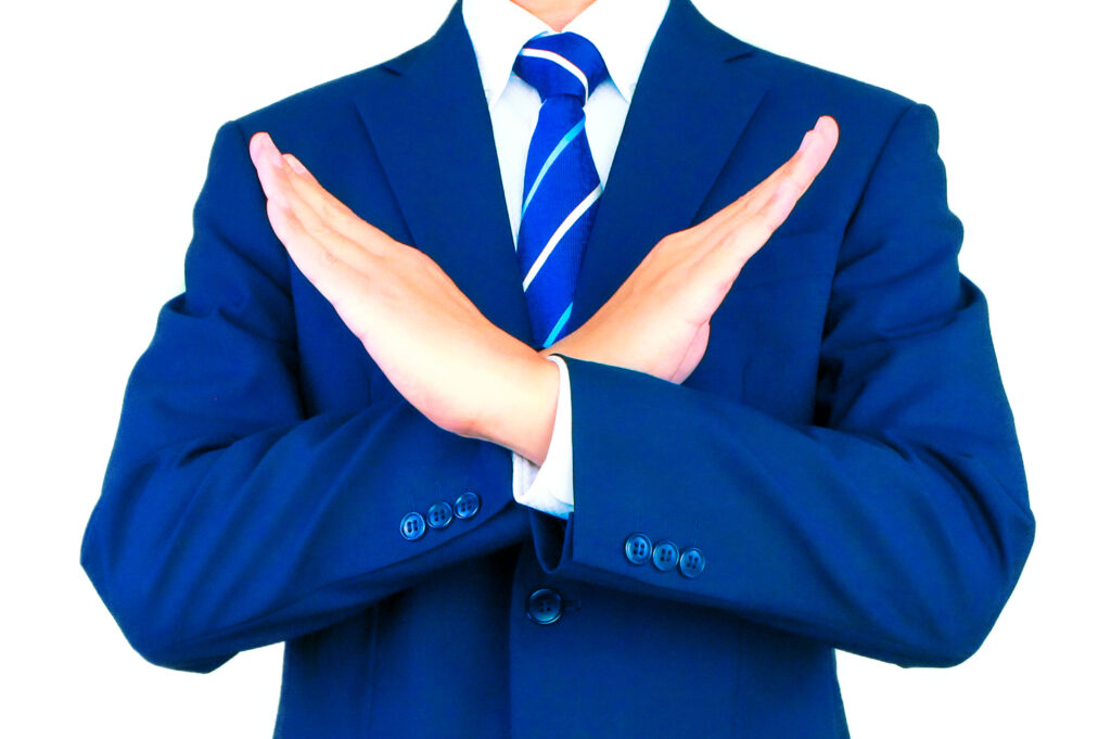 手でバツをするスーツのビジネスマン