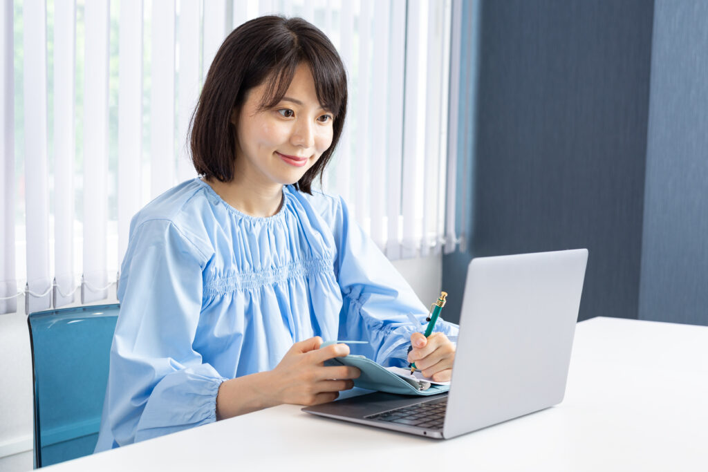 PCを操作しながらメモを取る女性