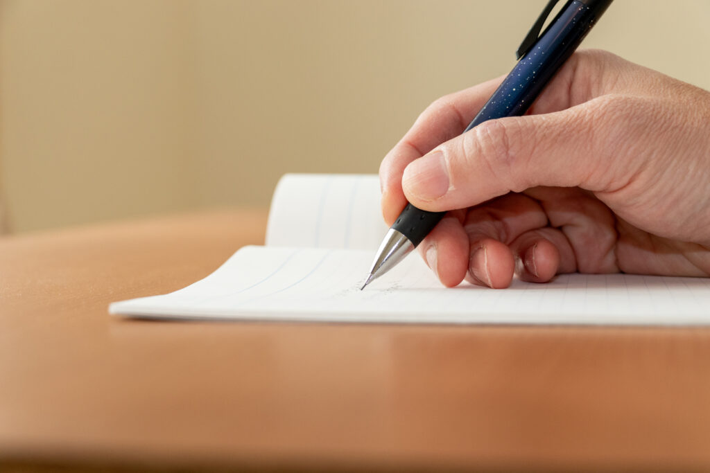 ノートに何か書き込む人の手元