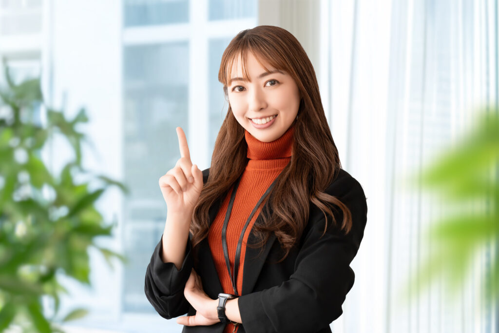 人差し指を立てて案内する笑顔の女性