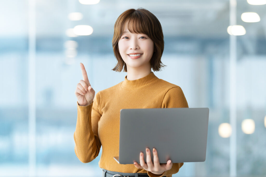 パソコンを持って案内をする笑顔の女性