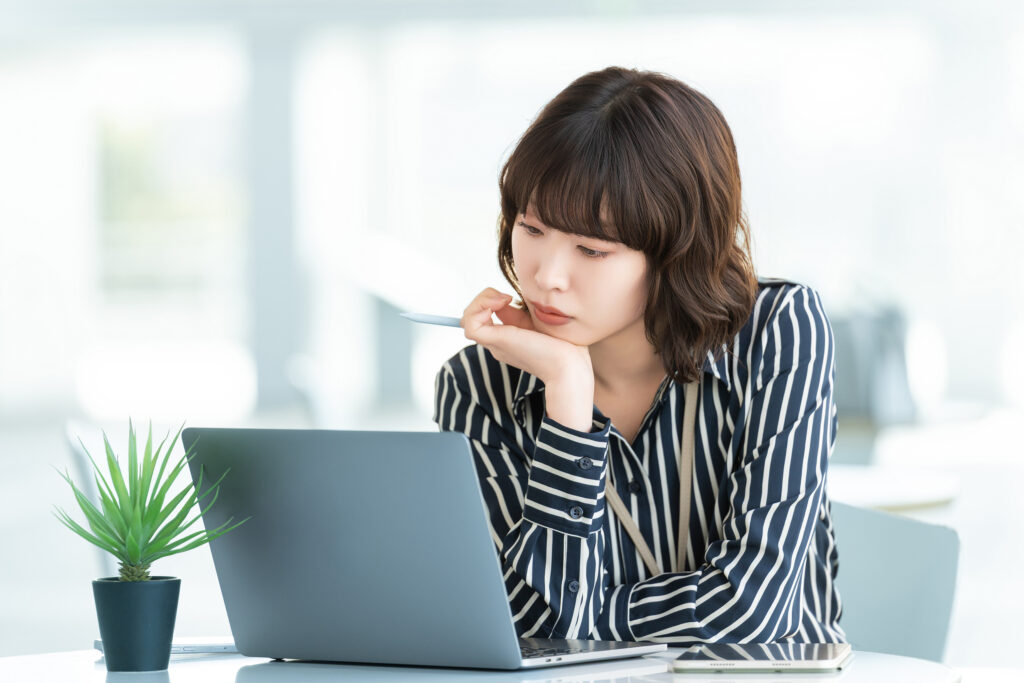 パソコンを使いながら考える女性