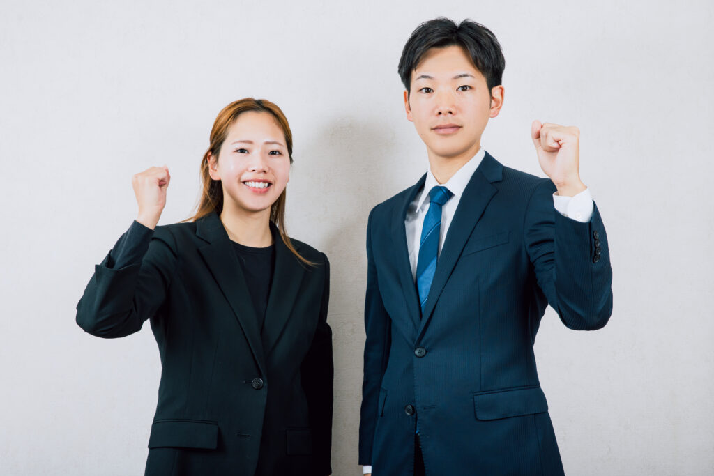 ガッツポーズするスーツの男女