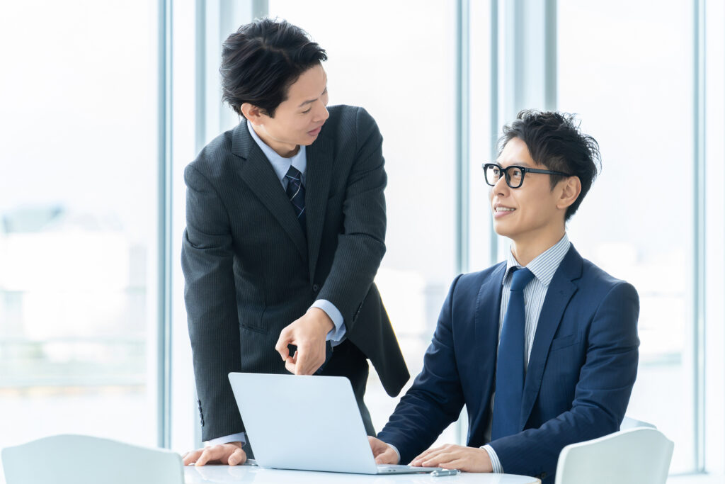パソコンで資料を見せるビジネスマン