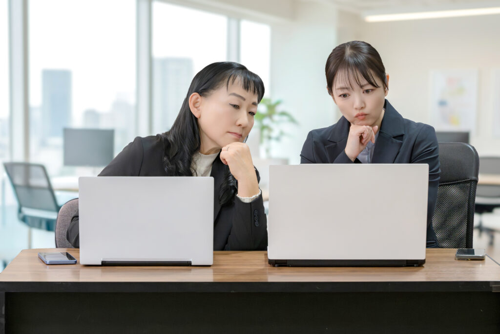 パソコンと考える二人のビジネスウーマン