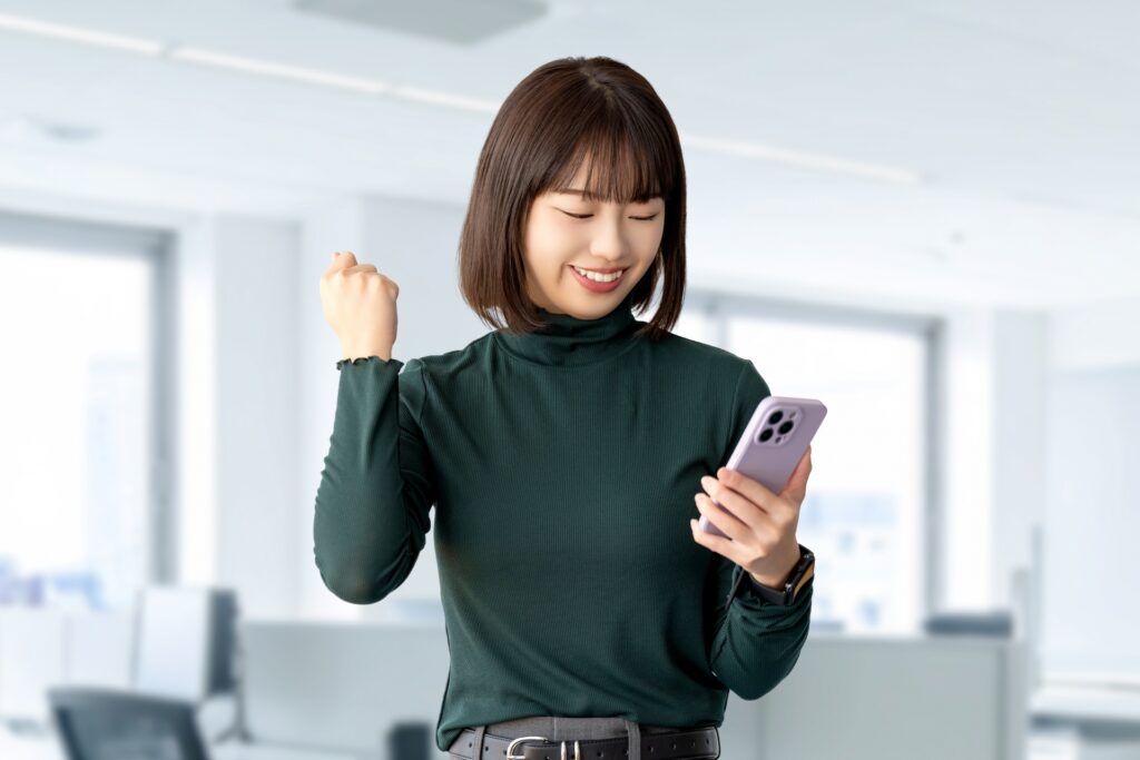 スマホを見て喜ぶ笑顔の女性ビジネスマン