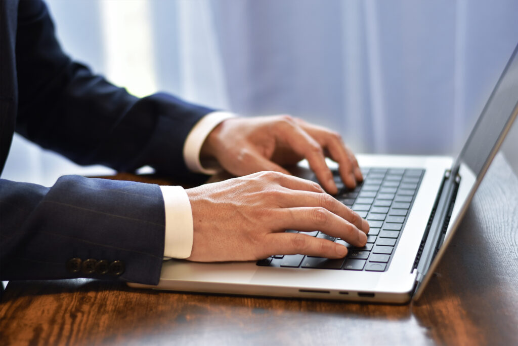ノートパソコンとタイピングする男性の手元