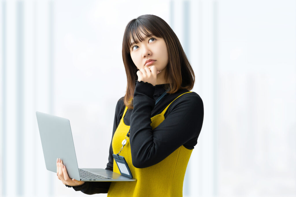 パソコンを持って考えるビジネスウーマン