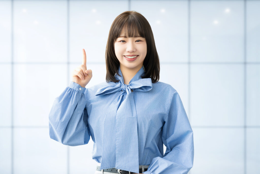 人差し指を立てて案内する笑顔の女性