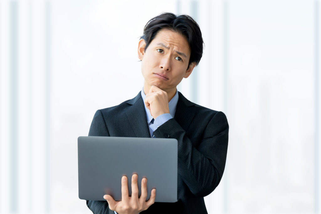 パソコンを使いながら悩む男性ビジネスマン