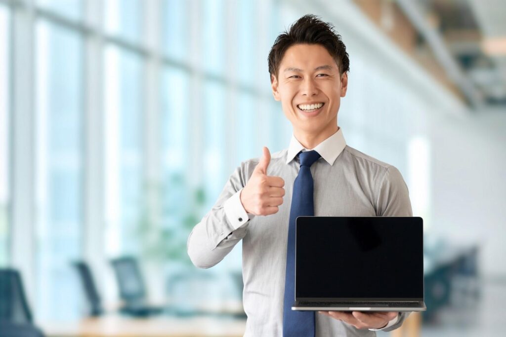 パソコンを持っていいねのポーズをする男性